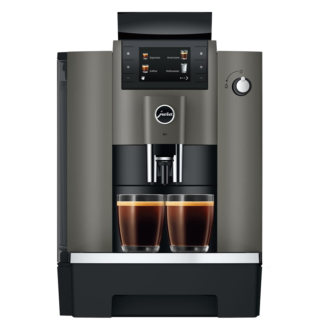 A modern automatic espresso machine in dark gray and black, shown from the front with two cups of espresso filled under the dispensing area on a white background.